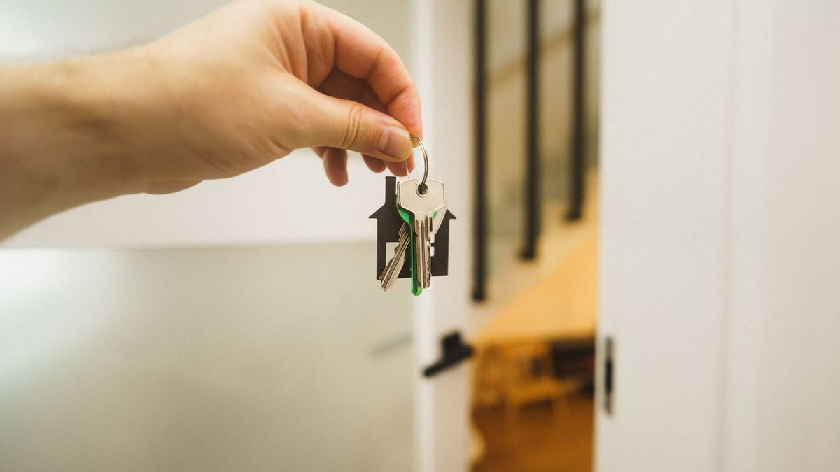 A hand holding a set of keys in a doorway