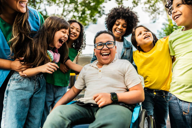 Joyful group of children, including a child in a wheelchair, laughing together outdoors